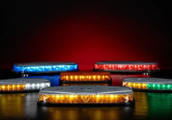 Colorful emergency vehicle light bars illuminated against a dark red background.