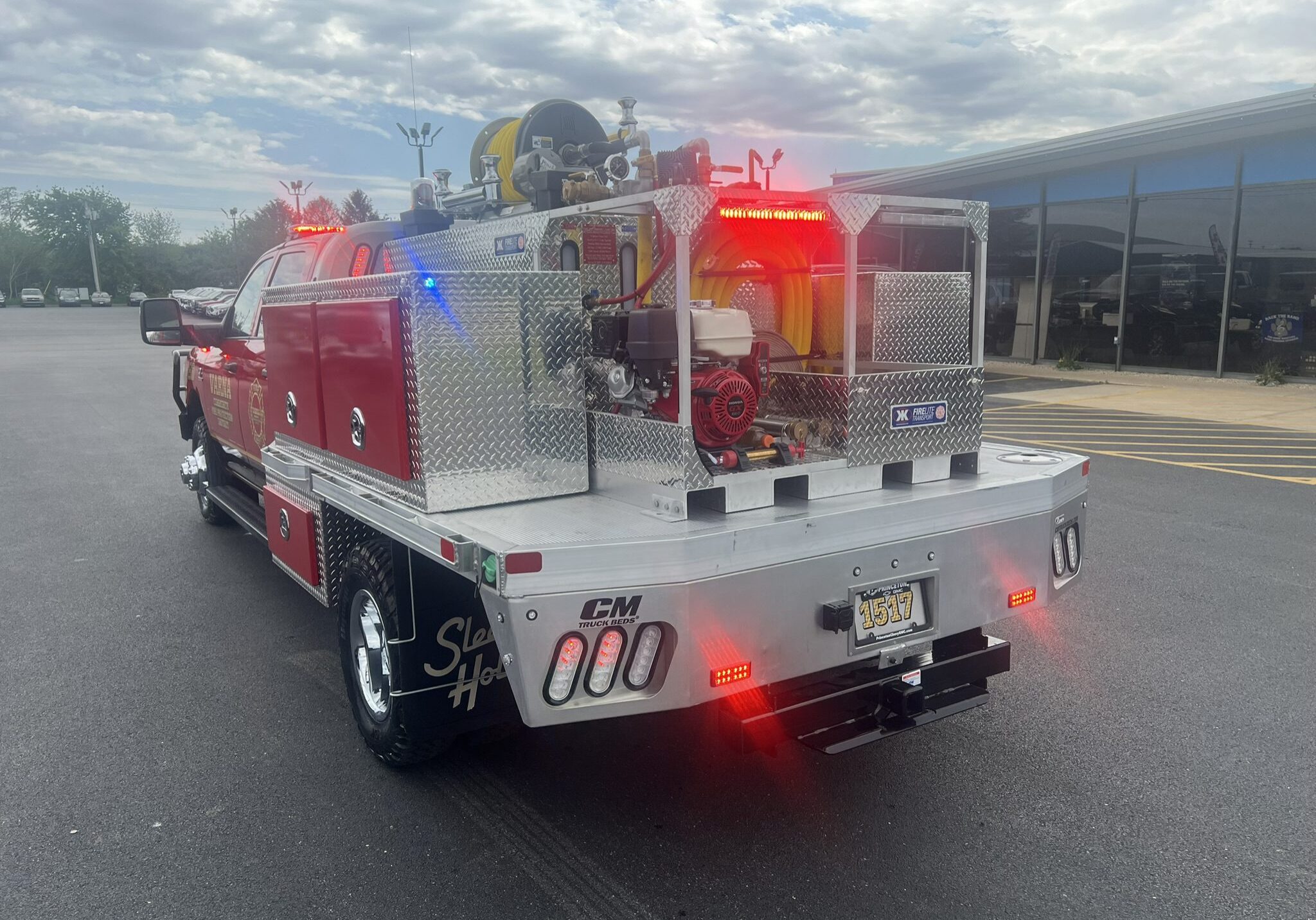 A red fire truck with emergency lights on under a cloudy sky.